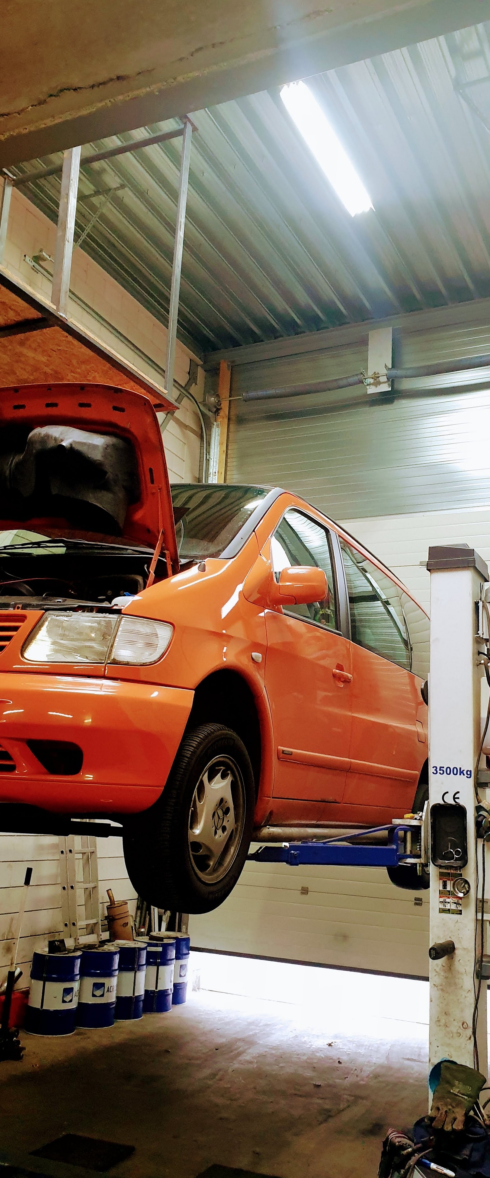 Oranje Mercedes Vito bestelbus op de hefbrug met open motorkap